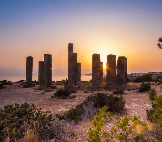 Ibiza Henge, basalt stone columns representing the solar system, sunset backdrop, near Cala Llentia, artistic landmark, Ibiza's cultural heritage.